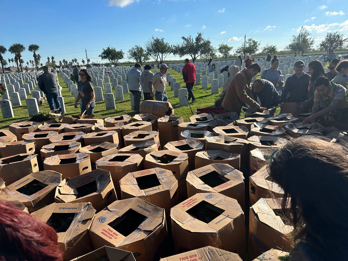 <p>Volunteers picking up bundles of wreaths to place at the headstones.</p>