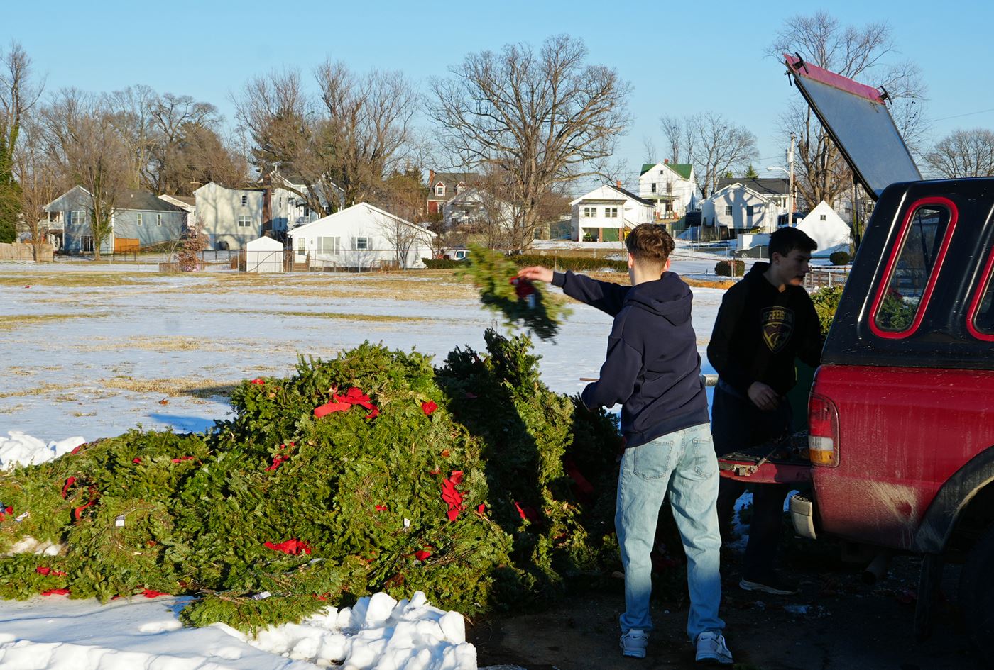 Volunteers unload wreaths from transport vehicle.