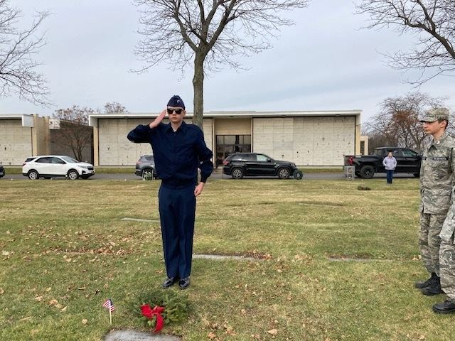 Cadet Clothier salutes after placing the wreath while Cadet Martin stands at attention.