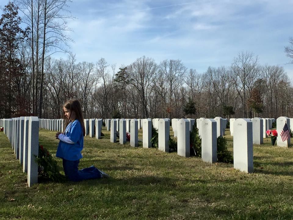Nora praying at the graves after placing wreaths.