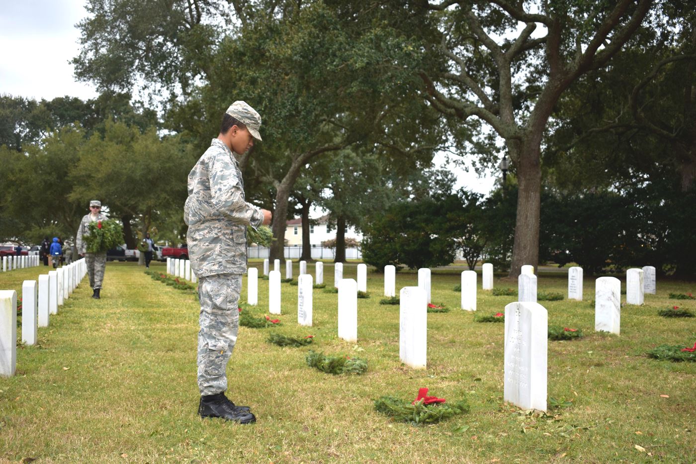 With reverence, a cadet carefully lays a wreath, honoring those who served our country, while another cadet continues the solemn duty in the background.