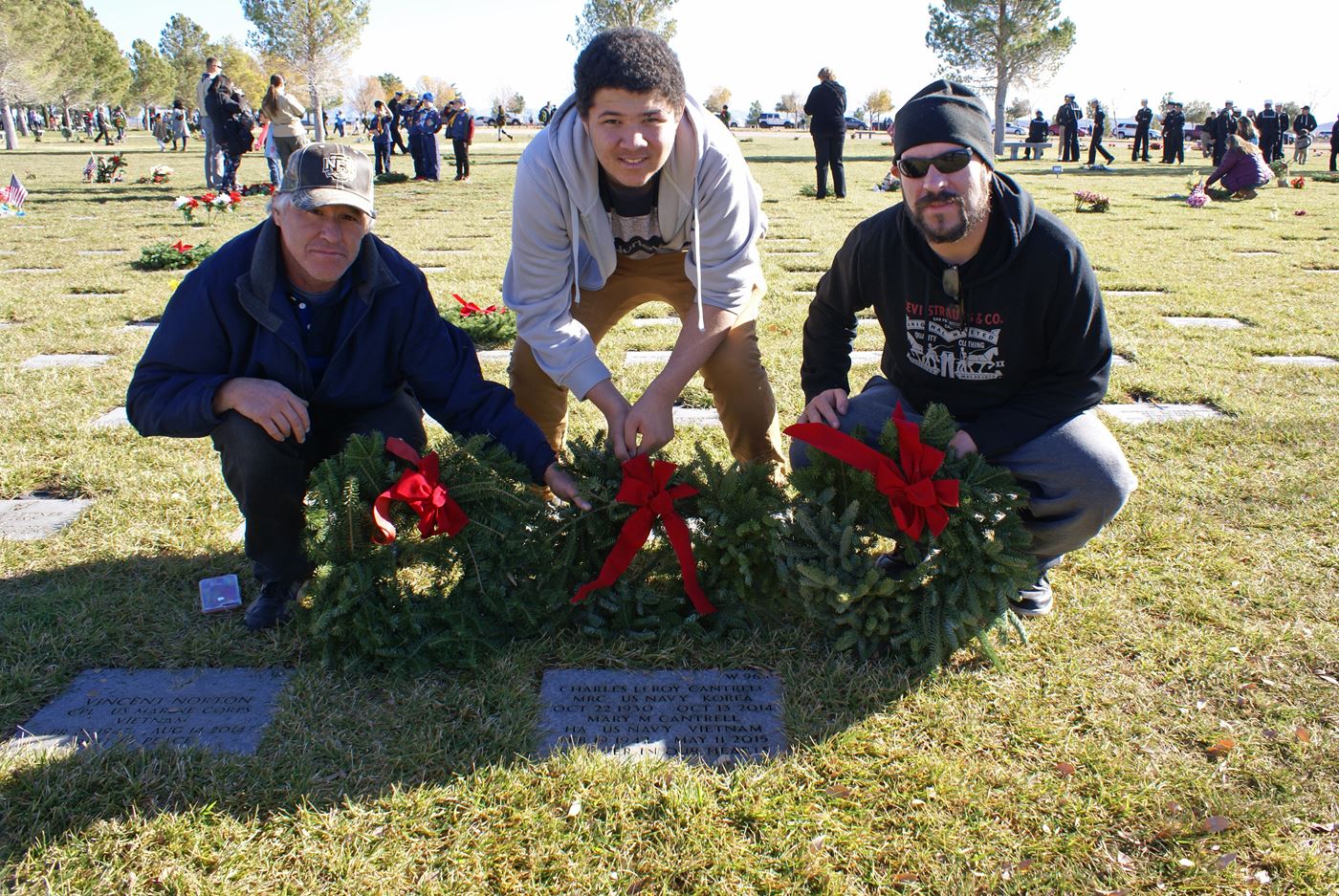 Brothers Tom and Sean Daly along with nephew Tyreese Daly place a wreath on their family's gravesite.