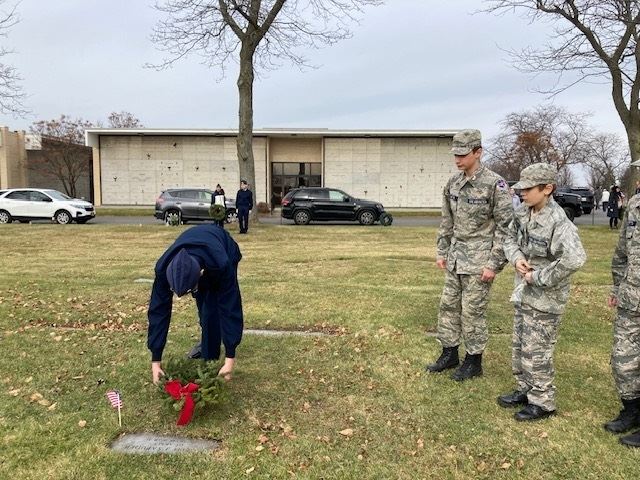 Cadets Clothier, Martin, and Daniels lay a wreath on a military grave.