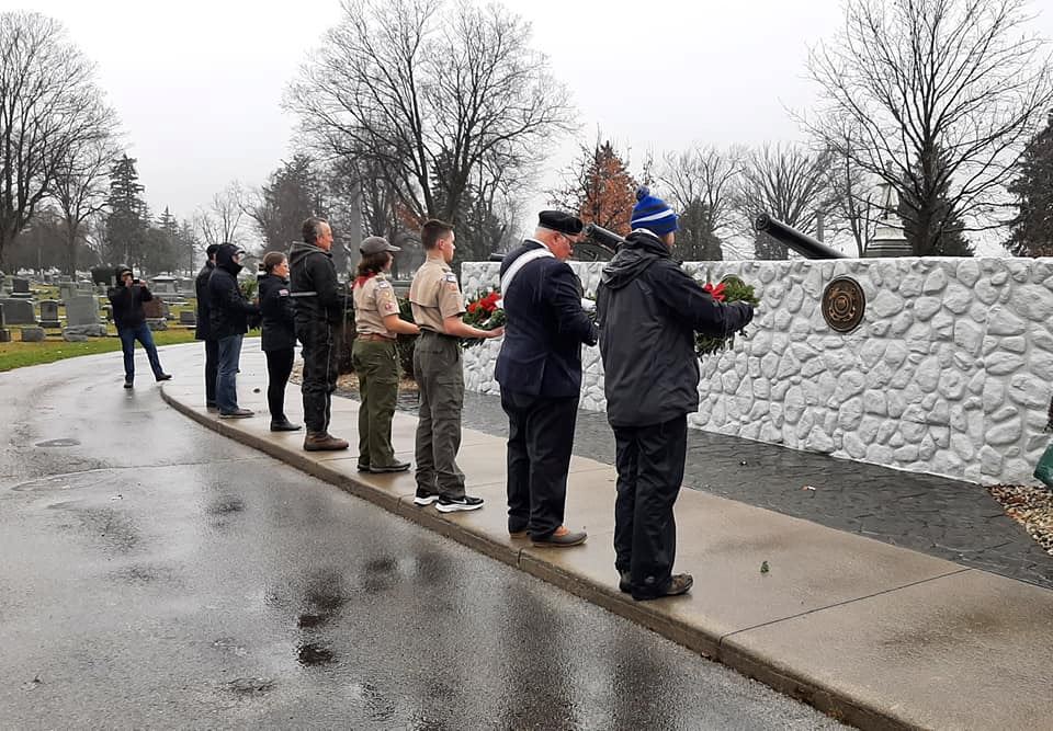 Volunteers lay wreaths on the Wall to Remember Memorial at Maple Grove Cemetery.