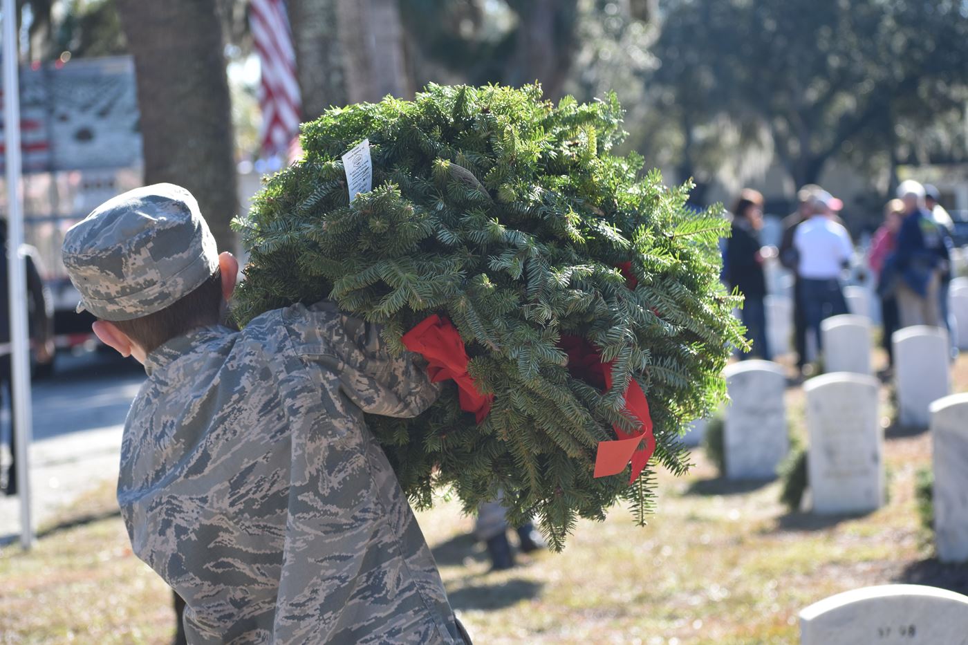 Cadet Qualls carries wreaths to a grave at Beaufort National Cemetery.