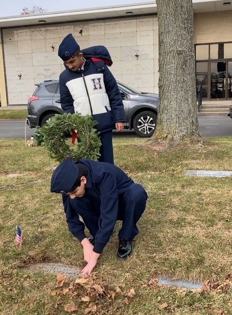 Cadet Stone cleans off the grave while Cadet Rayyan awaits the wreath placement.