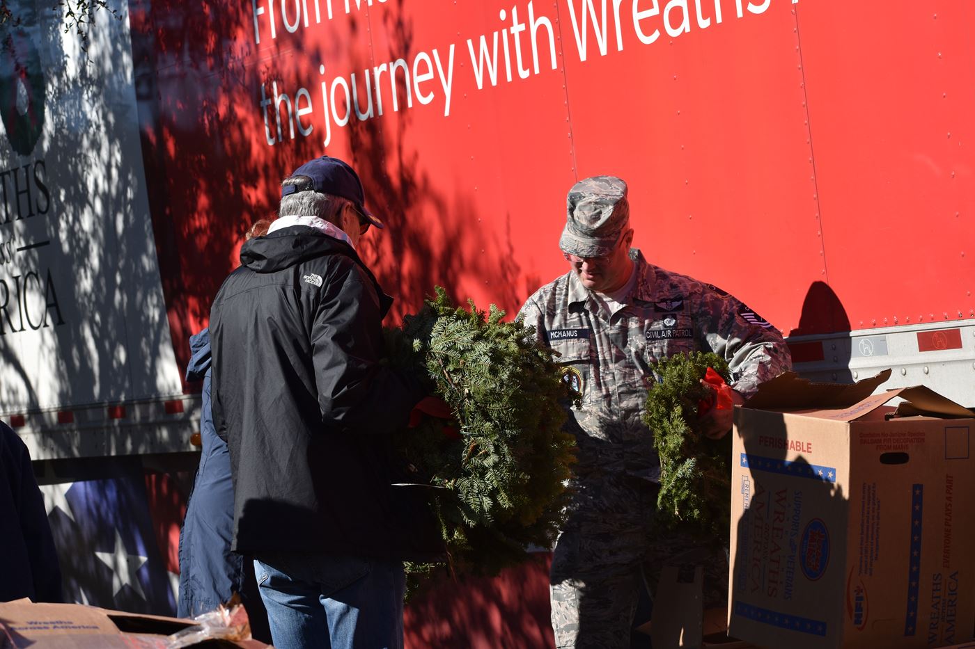 TSgt Dan McManus hands wreaths to another community volunteers