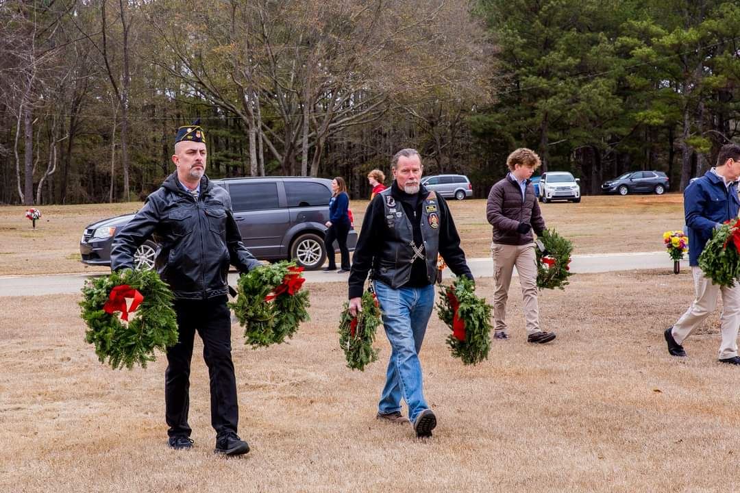 Volunteers carry wreaths to place on graves.