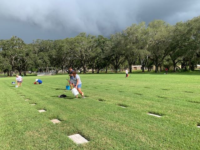 Despite looming storm clouds volunteers press on to clean up grave markers.