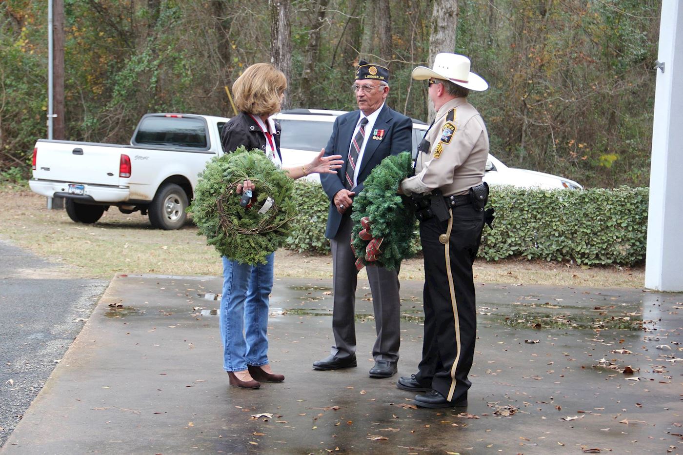 Member of ALA#113 holding wreath talking to Post #113 member and member of the Angelina County Sheriffs Department.  